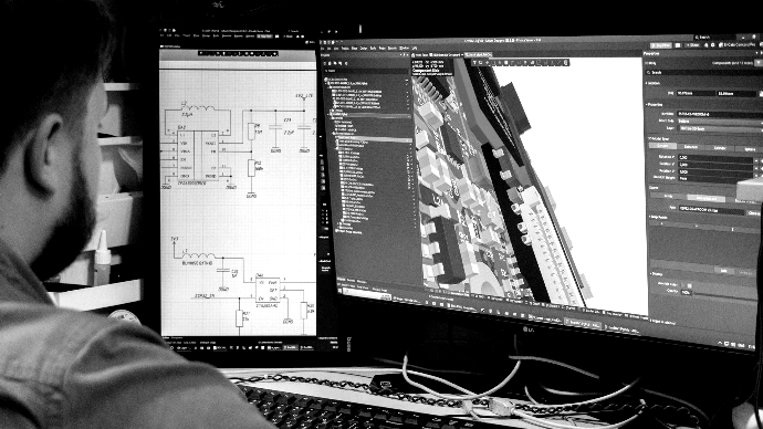 Design Phase Man looking at circuit board design on computer screen.